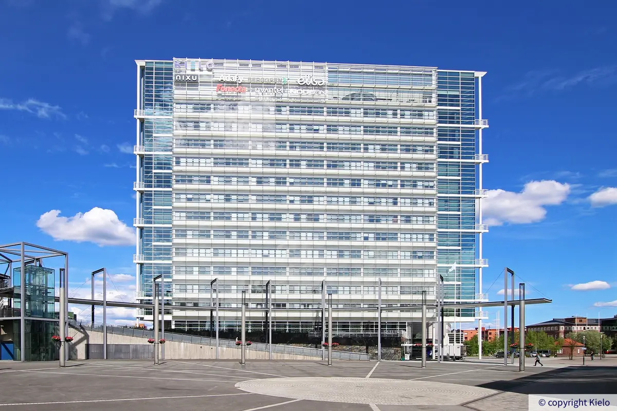 Innova 1 -toimitilakiinteistö. 15-kerroksinen toimistorakennus, jonka lasinen julkisivu hohtaa auringossa. Taustalla sininen taivas ja pilviä.